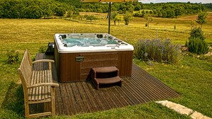 A hot tub with a wooden deck and a bench, surrounded by a grassy area and a large umbrella. - MULBERRY TREE Villa - Luxury Villa - Heated Pool, Hot tub, Gym, Garden, Calm (Carmensac, Meyrals)