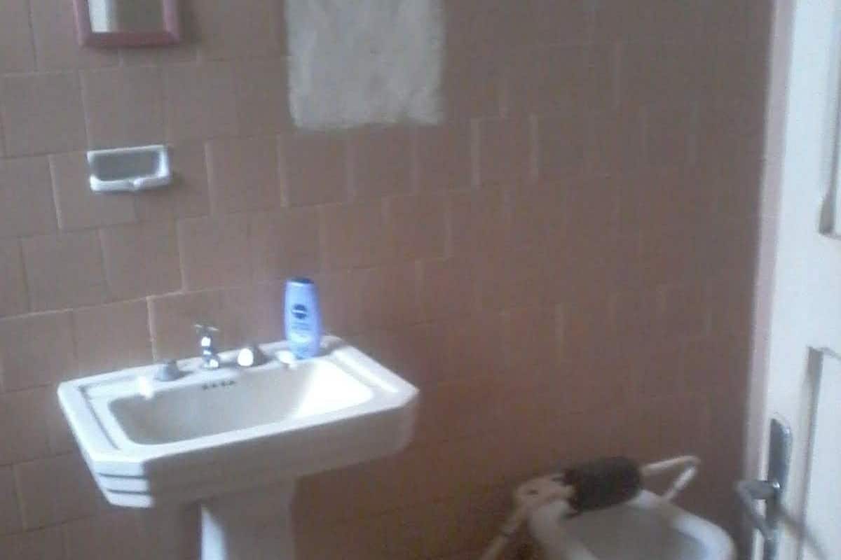 Un baño con lavamanos pedestal, un inodoro y un espejo en la pared.