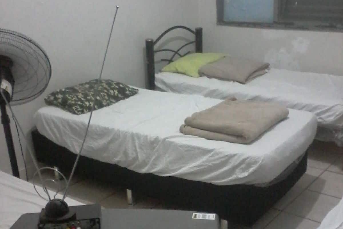 Una habitación con dos camas, televisión y ventilador.