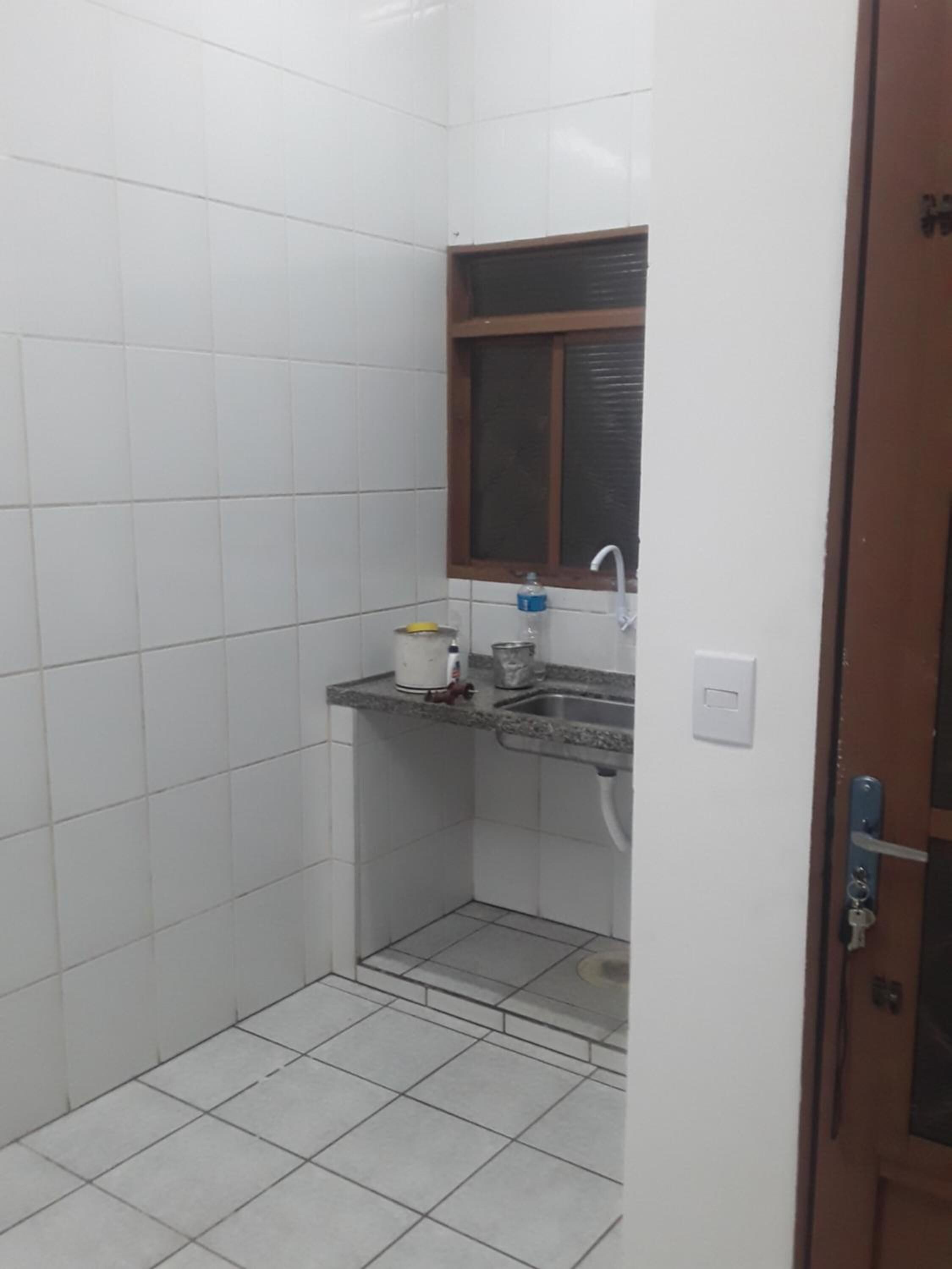 A small, tiled bathroom with a sink, a window, and a door.