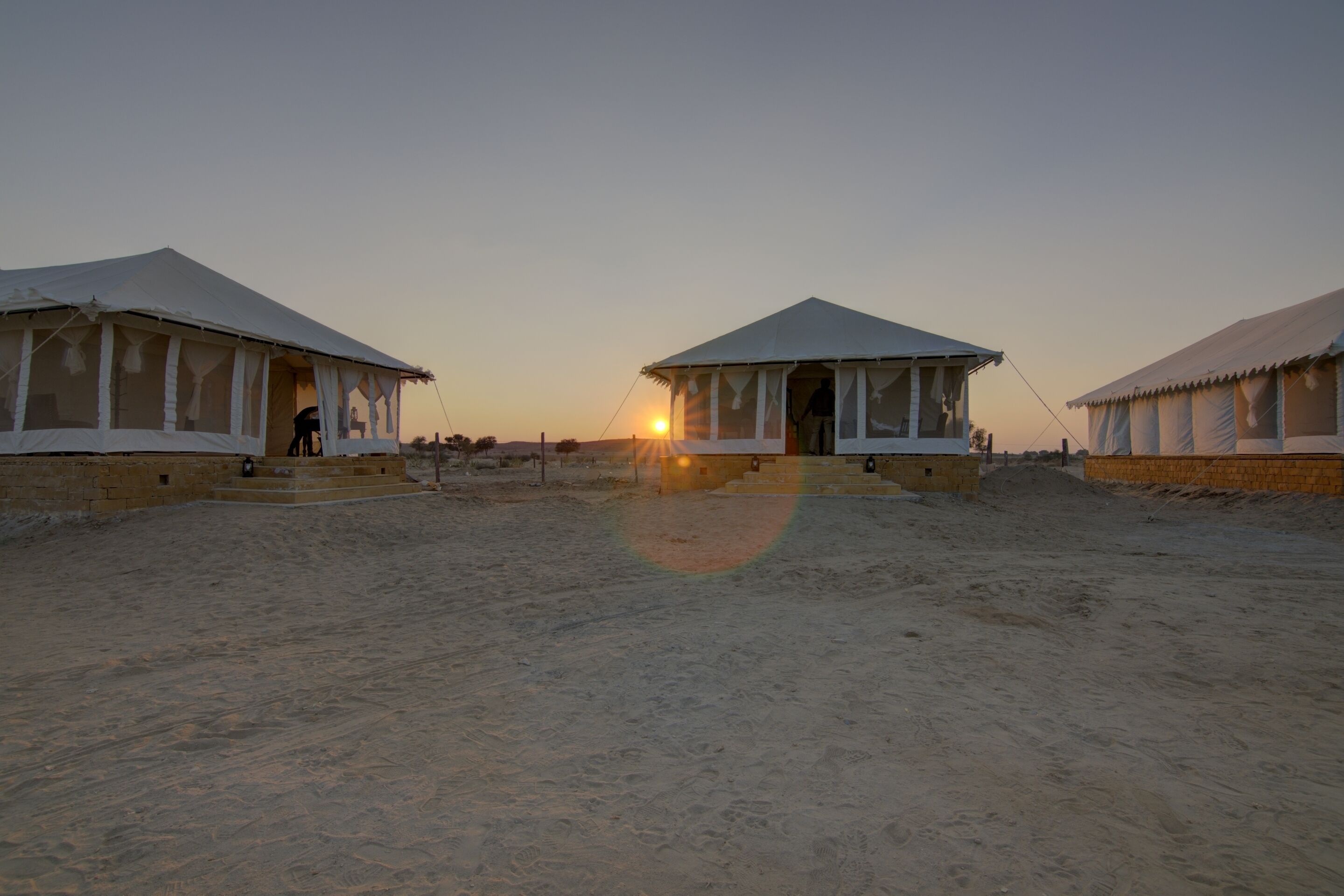Acampamento no deserto com tendas e céu limpo.