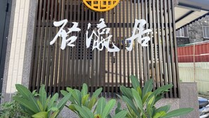 A building entrance with a large Chinese character sign, vertical slats, and a circular emblem above the sign. - Inn-itiate Tainan (Tainan)