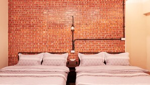 A room with two beds, a brick wall, and a hanging light fixture. - Inn-itiate Tainan (Tainan)
