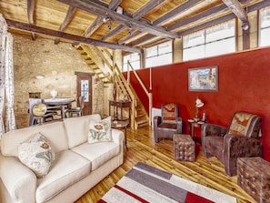 Ein gemütliches Zimmer mit Holzboden, roter Wand, einer Couch, einem Tisch und einer Treppe.