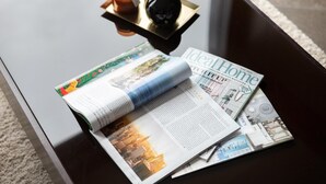 Una revista abierta sobre una mesa negra brillante, con una vela y un quemador de incienso.