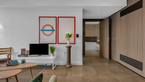 Una sala moderna con un televisor de pantalla plana, una mesita y un jarrón decorativo.