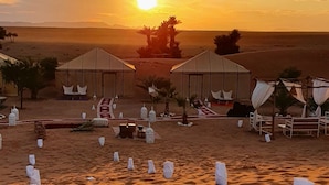 Paisaje desértico con tiendas de campaña y sillones, evocando un campamento o un complejo turístico.