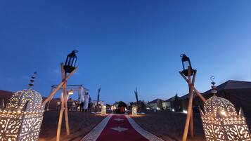 A carpeted pathway flanked by ornate lanterns leading to a building.