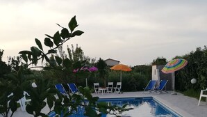 A swimming pool with tiled flooring, surrounded by lounge chairs and umbrellas. - Blue Pools Relax Casa Martina (Balestrate)