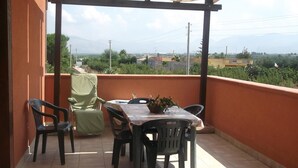 A covered balcony with a table and chairs, a potted plant, and a view of the surrounding landscape. - Blue Pools Relax Casa Martina (Balestrate)