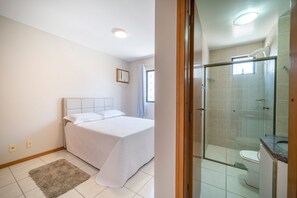 A bedroom with a bed, a bedside table, and a window.