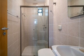 A bathroom with a glass-enclosed shower, a toilet, and a bathtub.