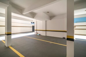 Un espacio interior amplio con paredes blancas, franjas amarillas y negras, y suelo gris.