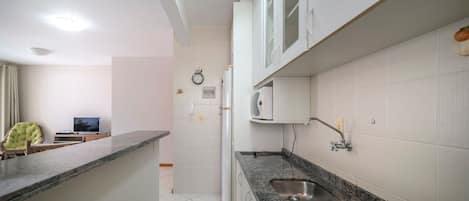 Una cocina moderna con armarios blancos, una encimera de granito y un lavamanos empotrado.