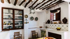 A rustic kitchen with exposed wooden beams, a hanging lantern, and a tiled backsplash.