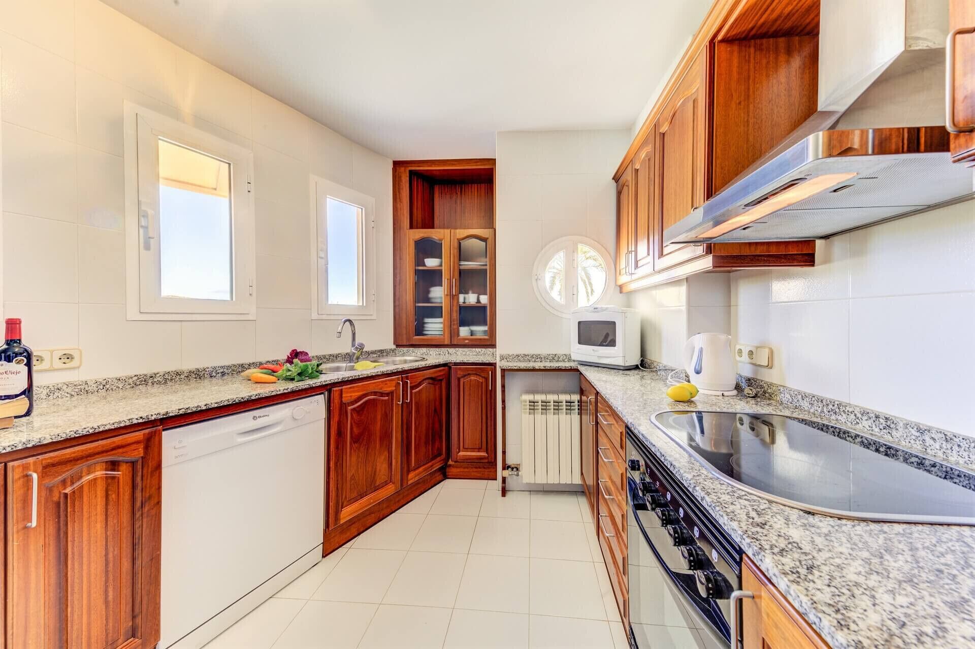 A modern kitchen with wooden cabinets, a granite countertop, a built-in oven, and a microwave.