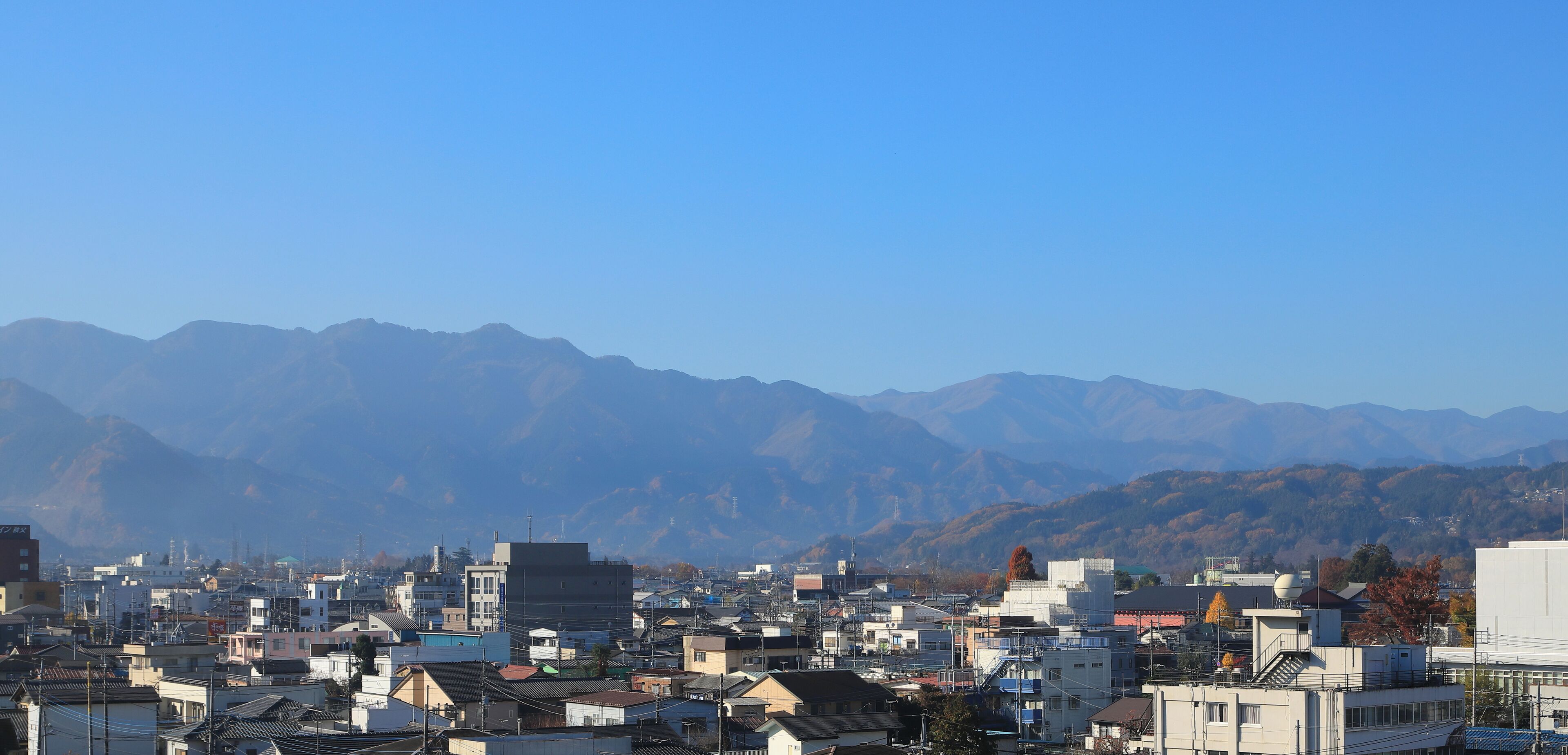 Un paisaje urbano con edificios y montañas al fondo.
