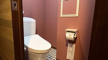 Un baño con inodoro, dispensador de toallas de papel y piso a cuadros.