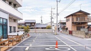 A parking lot with a wooden fence, a wheelchair-accessible path, and a row of buildings with traditional architecture. - Comfort Stay Miyabi (Chichibu)