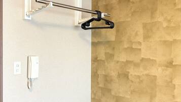 A hotel room with a wooden accent wall, a white telephone, and a black hanger on a white bracket.