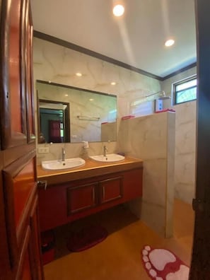 A bathroom with two sinks, a mirror, and a shower. - Sunset Bay Villas Siargao (General Luna)