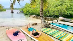 Een strandscène met surfplanken en een persoon die op een surfplank ligt.