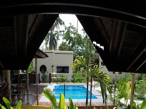 A pool area with a view of a building and tropical vegetation. - Sunset Bay Villas Siargao (General Luna)