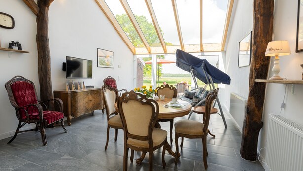 Un coin repas avec une table en bois, des chaises et un téléviseur fixé au mur.