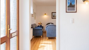 Une pièce avec deux fauteuils bleus, une lampe et un tableau encadré accroché au mur.