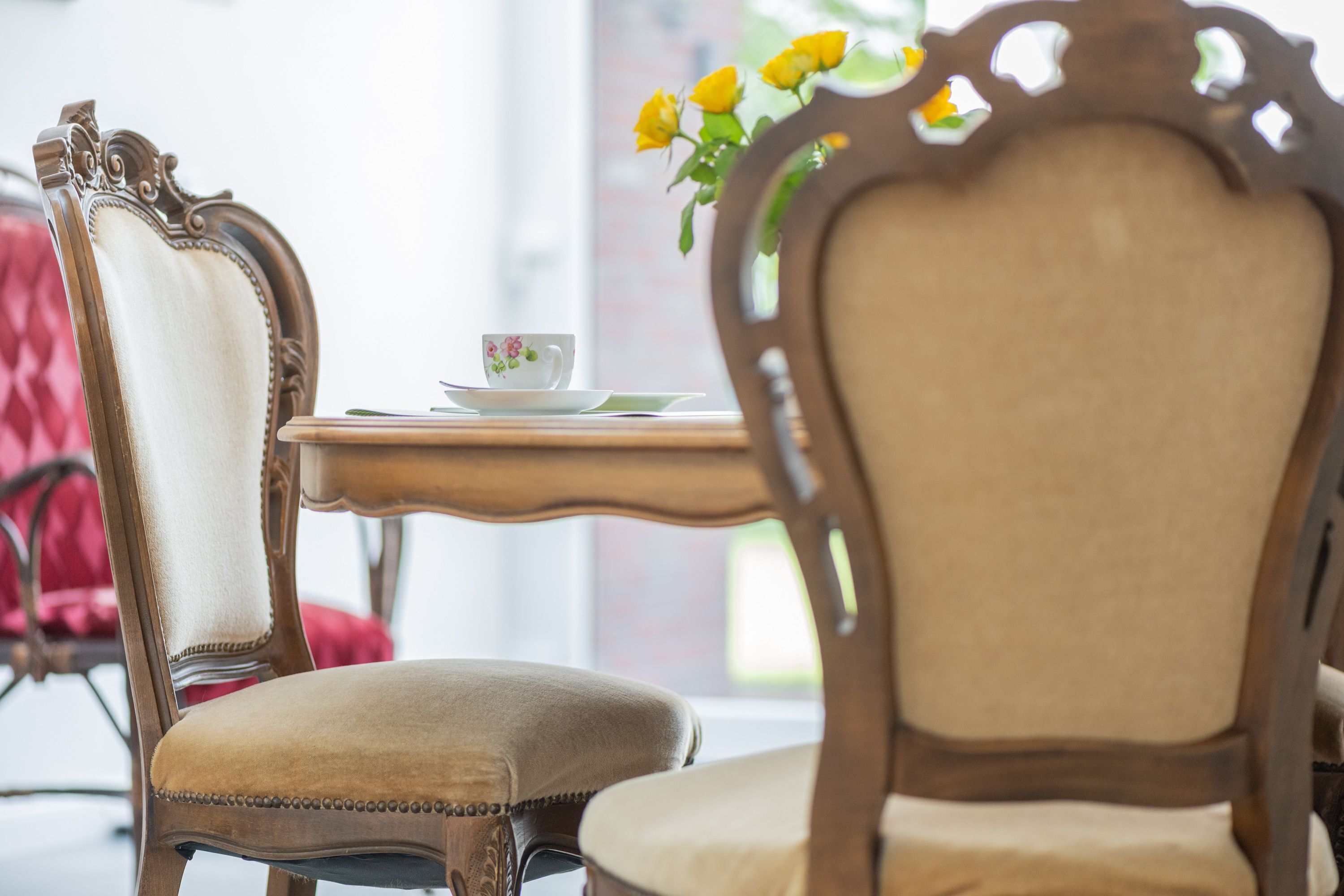 Ein Essbereich mit aufwendig geschnitzten Holzstühlen und einem Tisch mit einer Blumenvase.