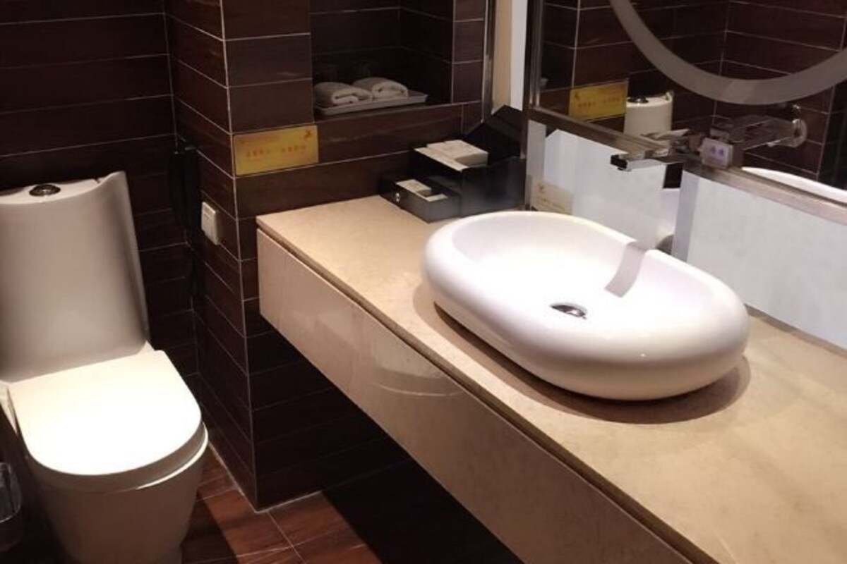 A modern bathroom with a toilet, a sink, and a mirror.