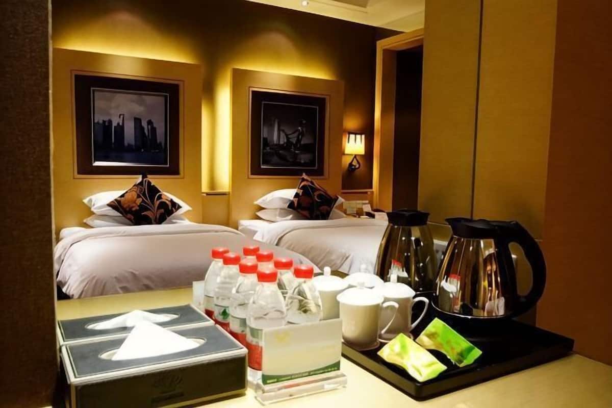 A hotel room with two beds, a coffee maker, and a tray with breakfast items.