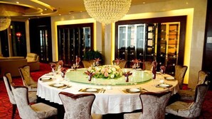 A round dining table with white tablecloths, surrounded by upholstered chairs. - Zhengyuan Mingyin International Hotel (Tai'an)
