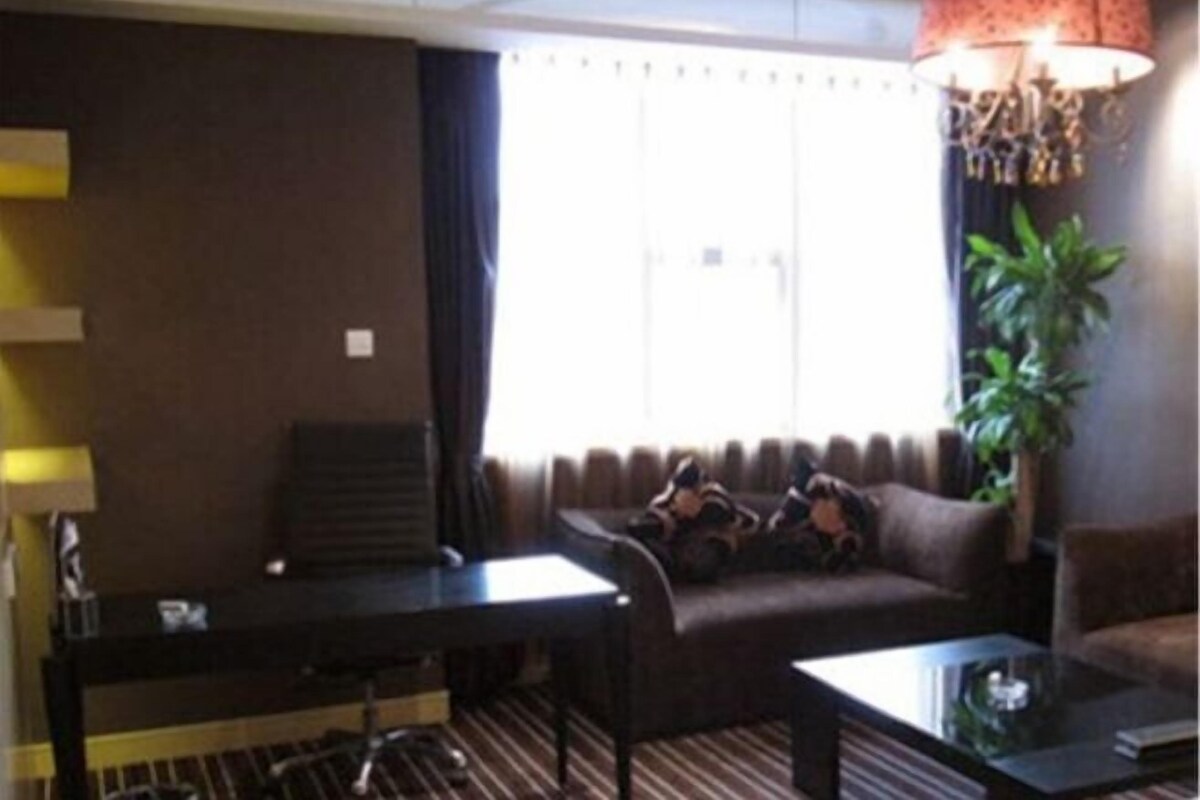A hotel room with a sofa, a small table, a lamp, and a plant.
