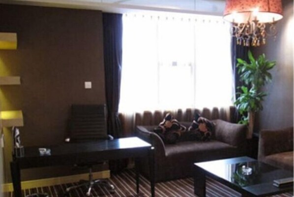 A hotel room with a sofa, a small table, a lamp, and a plant.
