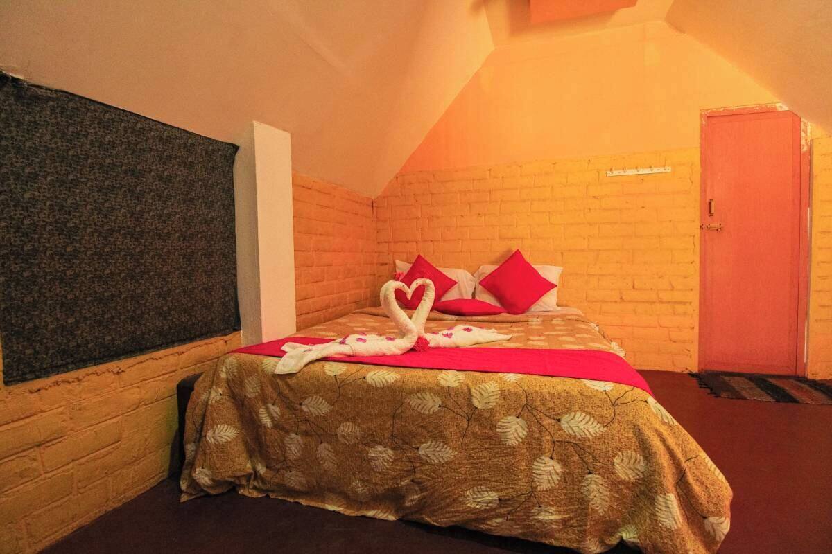 Um quarto acolhedor com uma cama, uma porta vermelha e uma parede de tijolos.
