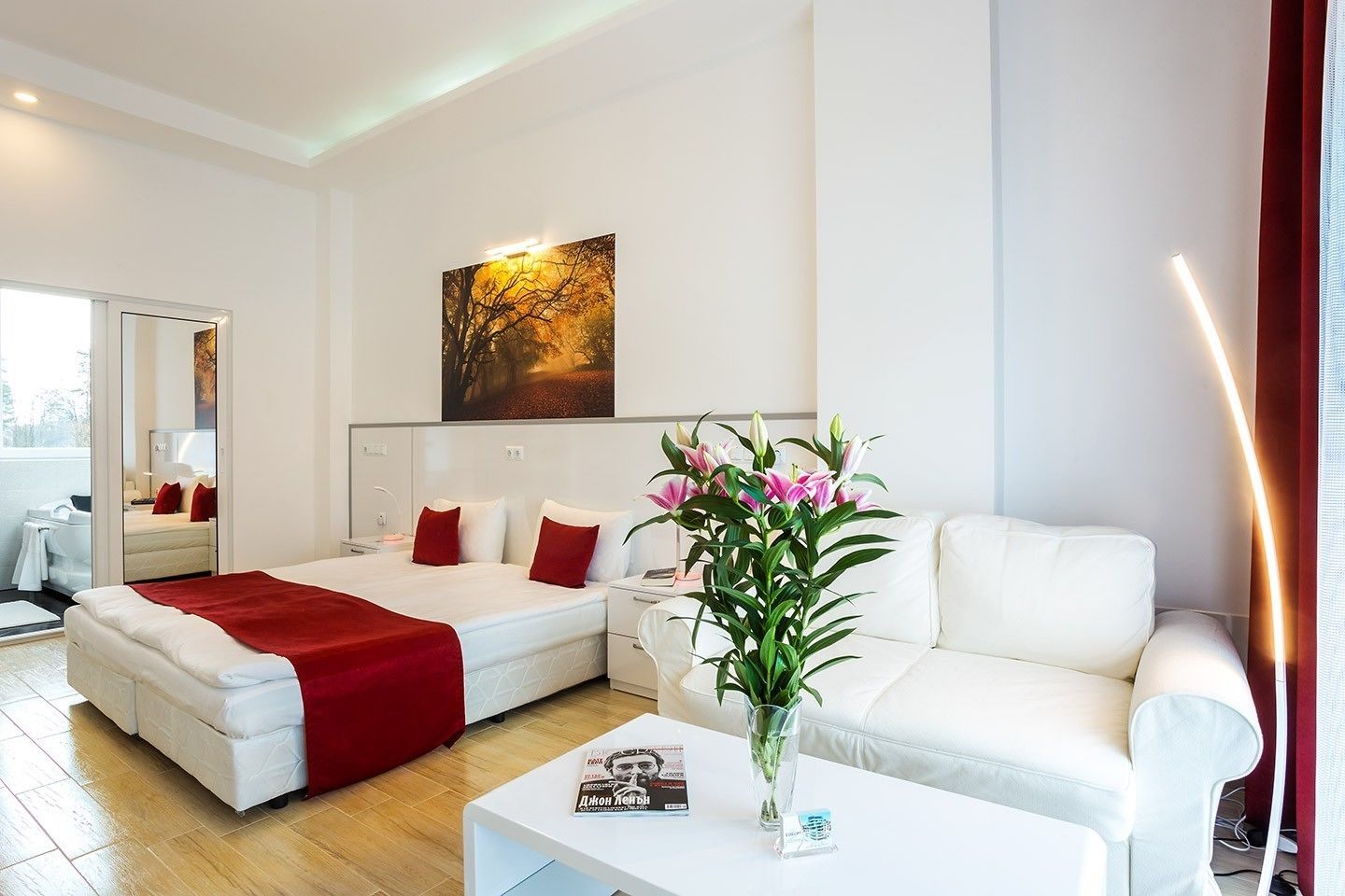 Ein modernes Hotelzimmer mit Bett, Sofa, Couchtisch und einem Gemälde an der Wand.