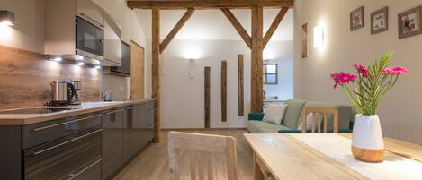A modern kitchen with wooden beams, a dining table, and a vase with flowers.