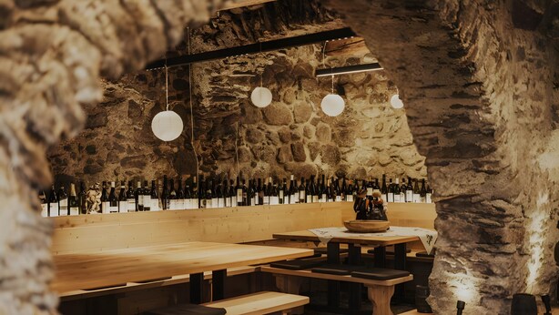 Un intérieur rustique avec des murs en pierre, des bancs en bois et des luminaires suspendus.