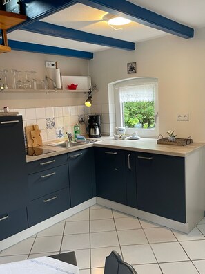 A modern kitchen with dark cabinets, a tiled backsplash, a coffee maker, and a window with a view of greenery.