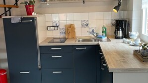 Ett litet, praktiskt kök med diskho, spis och skåp.