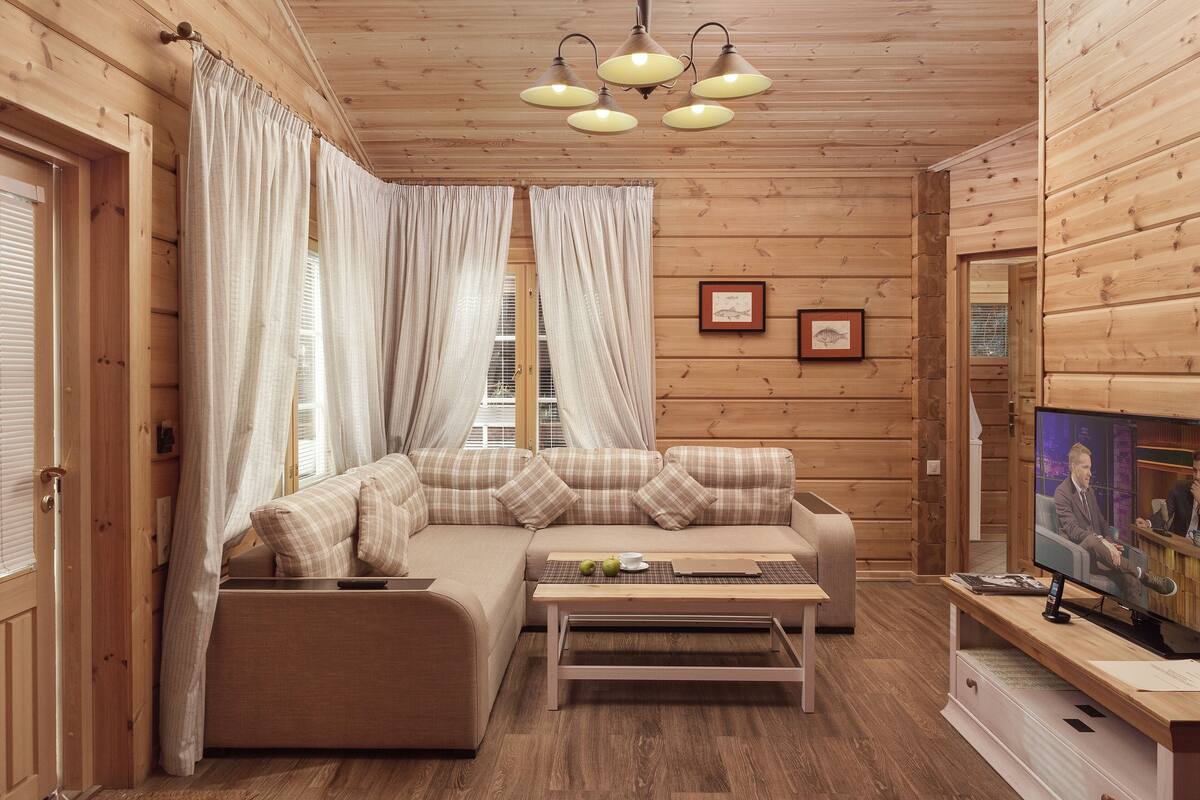 Une pièce confortable, aménagée comme un chalet, avec un canapé, une table basse et un téléviseur.