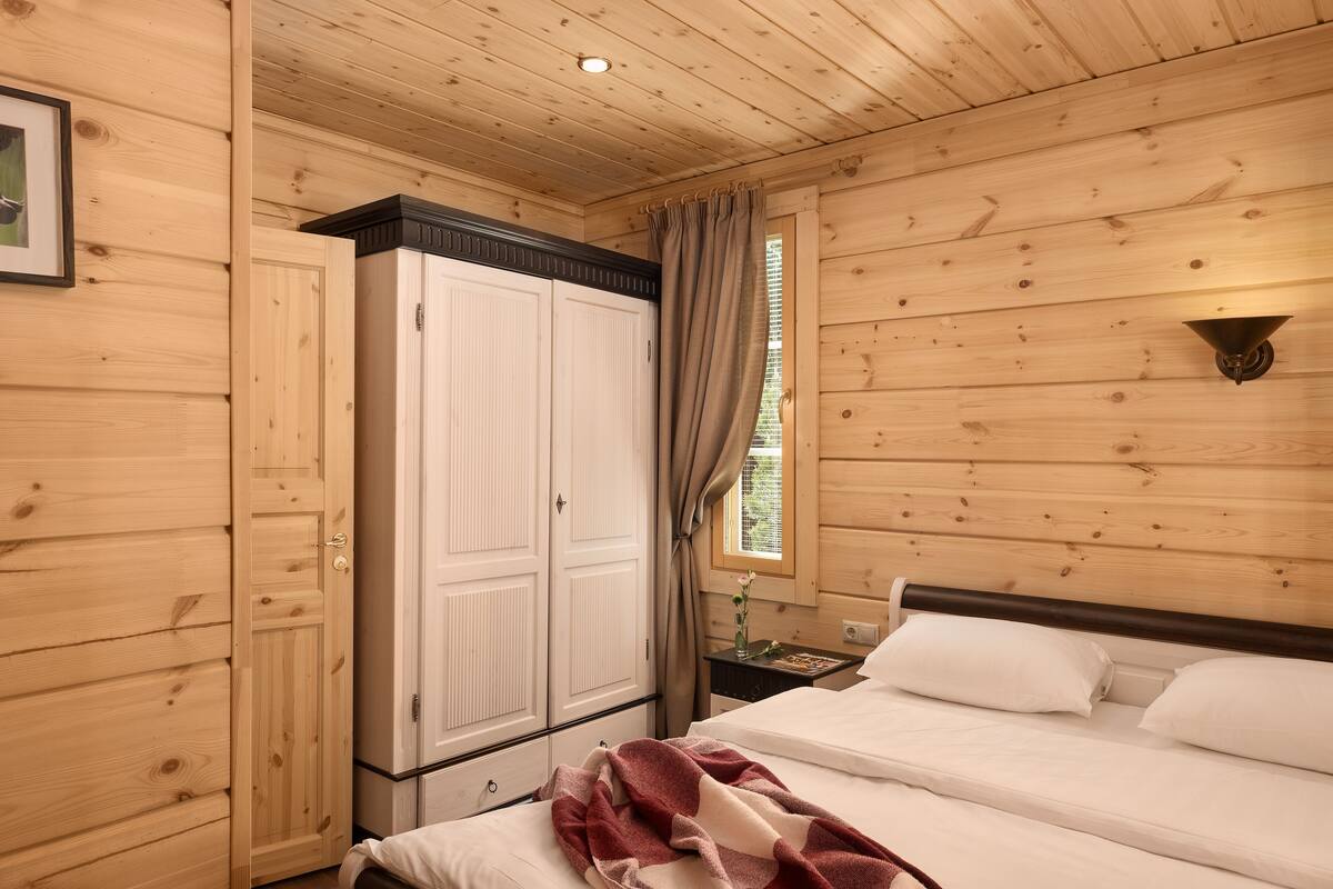 Une chambre à coucher aux murs lambrissés, avec un lit, une table de chevet et une armoire.
