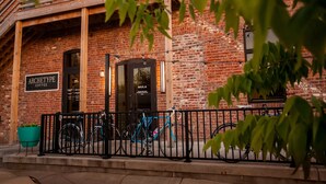 Un edificio de ladrillo con un letrero que dice "ARCHETYPE COFFEE" y una puerta con la leyenda "MULA". Hay bicicletas estacionadas en la parte delantera.