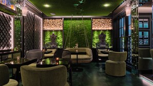 Een modern interieur met een groene wand, zitplaatsen en een hanglamp.