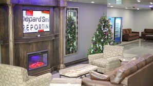 A lobby with a fireplace, seating area, Christmas tree, and a television displaying 'Depard Smith REPORTING'. - American Inn and Suites Ferndale (Ferndale)