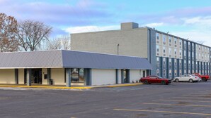A parking lot with a building featuring a flat roof and a brick facade. - American Inn and Suites Ferndale (Ferndale)