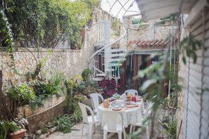 A patio with a table set for breakfast, surrounded by potted plants and a stone wall. - B&B Marchese (Taviano)