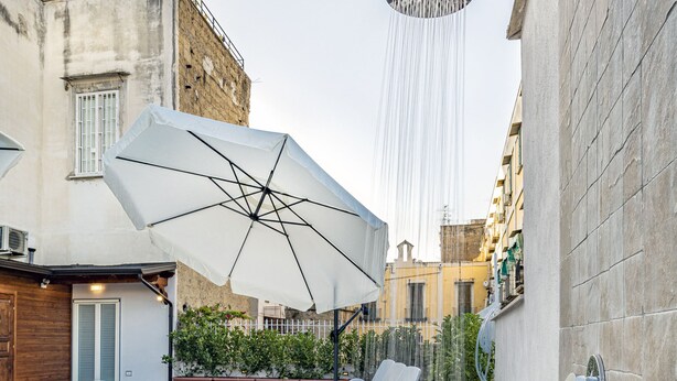 A rooftop terrace with a shower, outdoor seating, and potted plants. - Napoli Squares Suites (Naples)