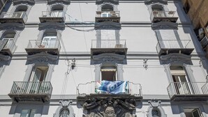 A building with a central entrance, multiple balconies, and a cobblestone street. - Napoli Squares Suites (Naples)